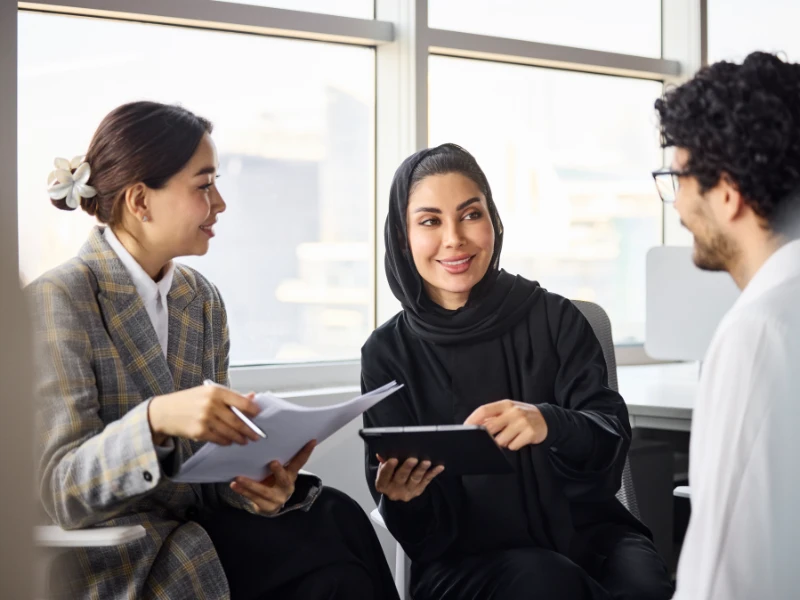 Smiling middle eastern businesswoman sitting with colleagues